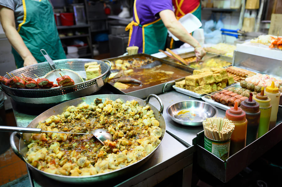 Puestos de comida callejera china iluminados de noche.