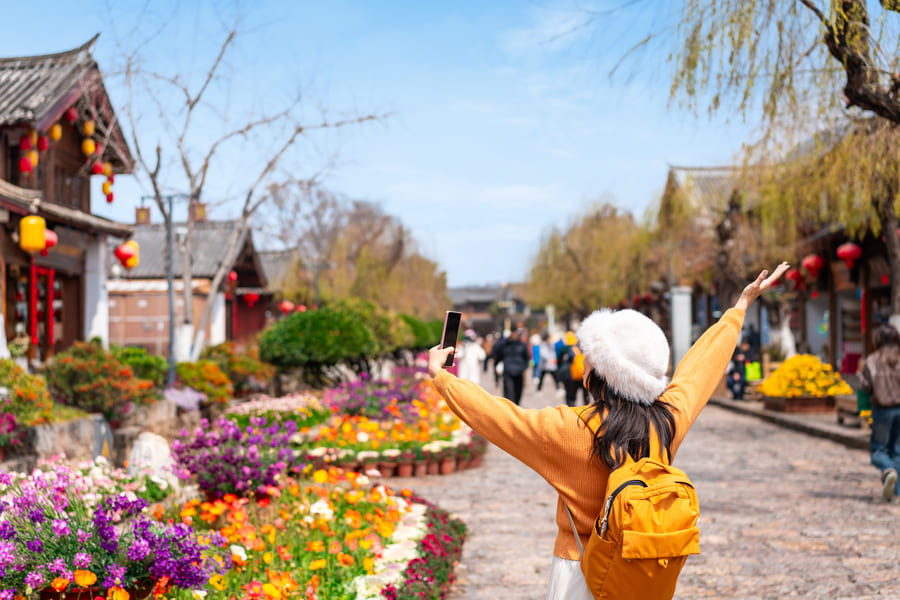 Turista disfrutando de los paisajes coloridos y jardines tradicionales en la región de Yunnan.